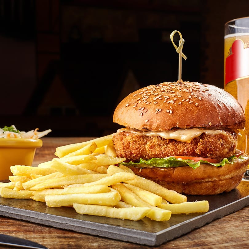 Crispy chicken burger with lettuce, tomato, and sauce, served with fries and coleslaw.