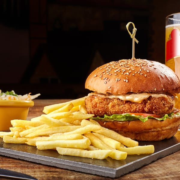 Crispy chicken burger with lettuce, tomato, and sauce, served with golden fries and coleslaw.