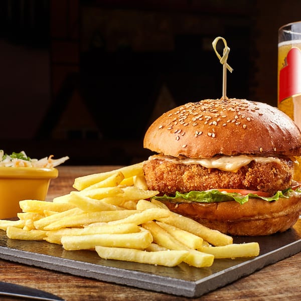 Crispy chicken burger with lettuce, tomato, and sauce, served with fries and coleslaw.