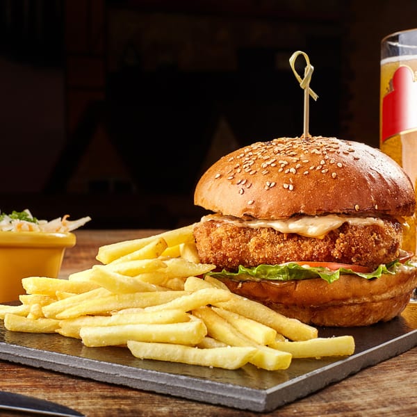 Crispy chicken burger with lettuce, tomato, and sauce, served with fries and coleslaw.